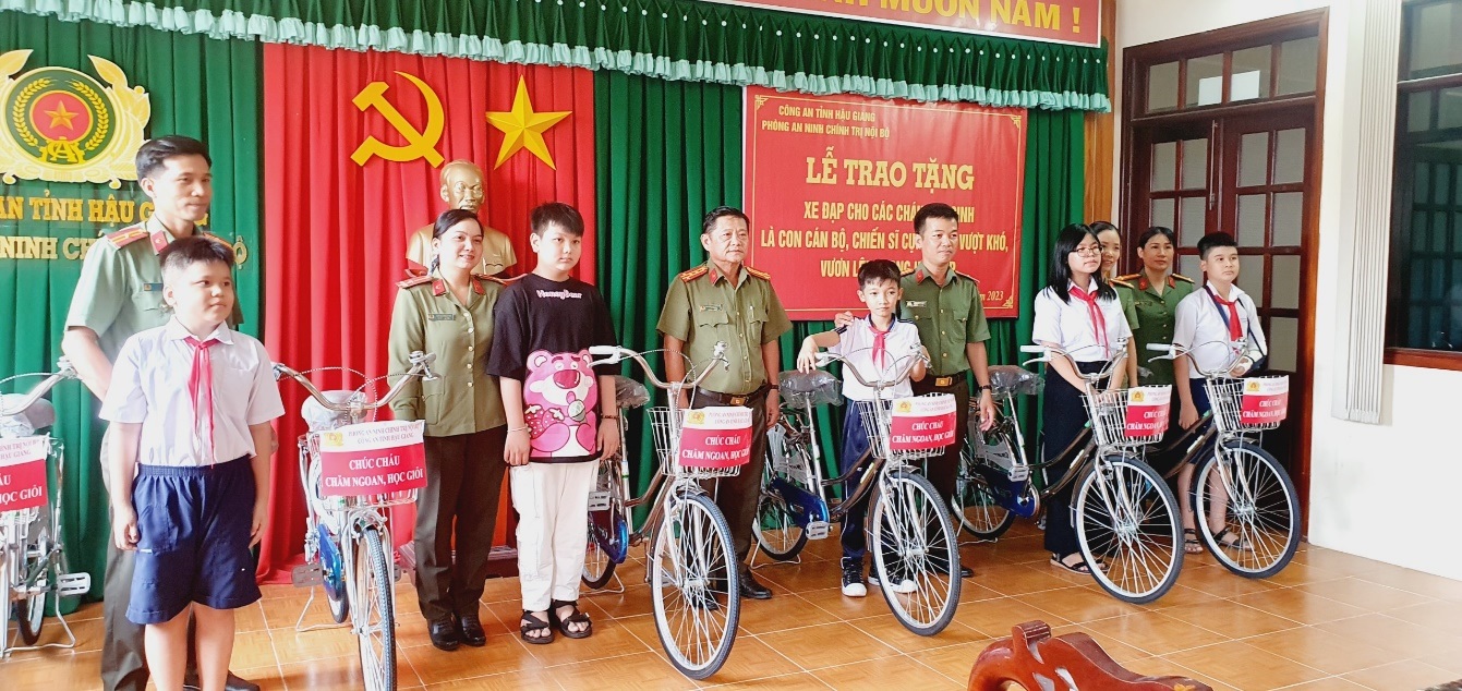 Đồng chí Đại tá Nguyễn Hoàng Lợi, Trưởng phòng An ninh chính trị nội bộ tặng quà và chụp ảnh lưu niệm cùng các cháu học sinh